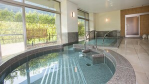 A modern indoor swimming pool with clear glass walls, a stone floor, and a view of greenery outside. - Kinu No Keikoku Hekiryu (Nikko)