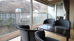 A balcony with a view of a mountainous area, a table, and two chairs.