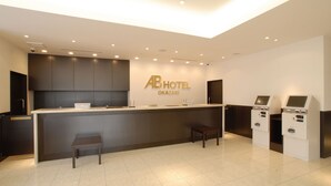 A hotel reception desk with a digital kiosk, a small seating area, and a sign for AB Hotel Okazaki. - Ab Hotel Okazaki (Okazaki)