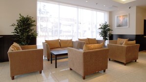 A modern hotel lobby with sofas, a coffee table, large windows, and indoor plants. - Ab Hotel Okazaki (Okazaki)