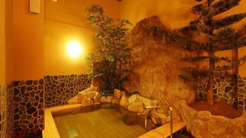 A spa room with a hot tub, stone walls, and a rock formation.