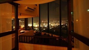 Une pièce dotée d’une grande fenêtre donnant sur une vue panoramique de la ville la nuit.
