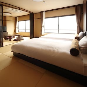 A hotel room with a large bed, a desk, and a view of the outside.