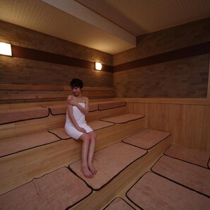 A person sitting on a bench in a room with wooden walls and benches.