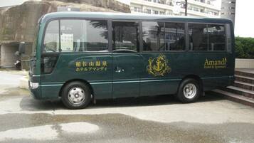 A green bus with 'Amandi Hotel & Sparesort' branding, parked on a wet road with a building in the background.