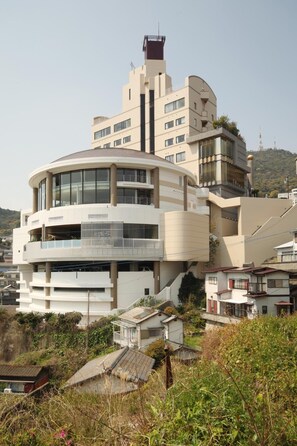 A multi-story building with a curved facade, balconies, and a prominent tower-like structure.