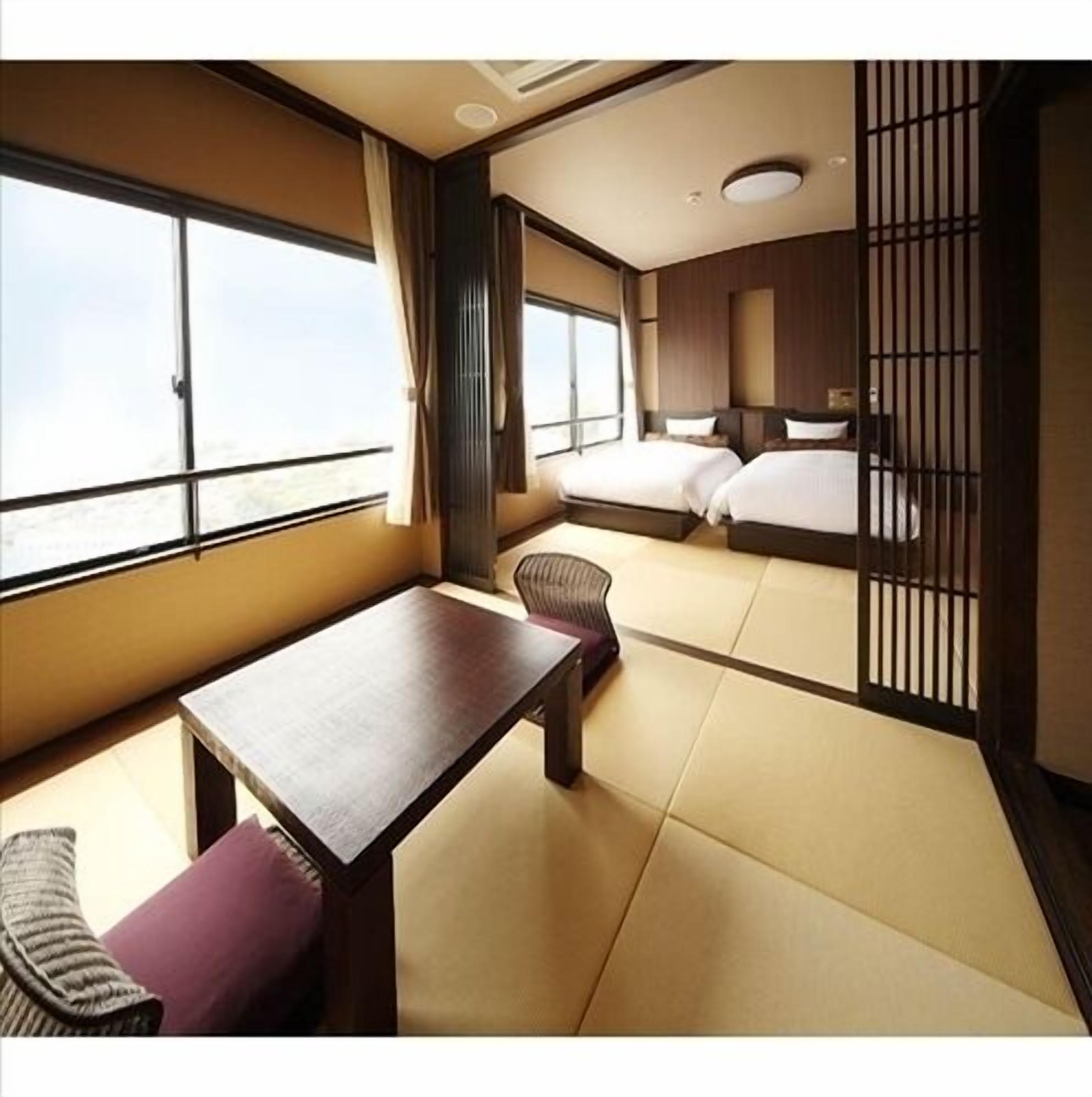 Una habitación de hotel con un ventanal grande, una mesa de madera, un sofá y una cama.