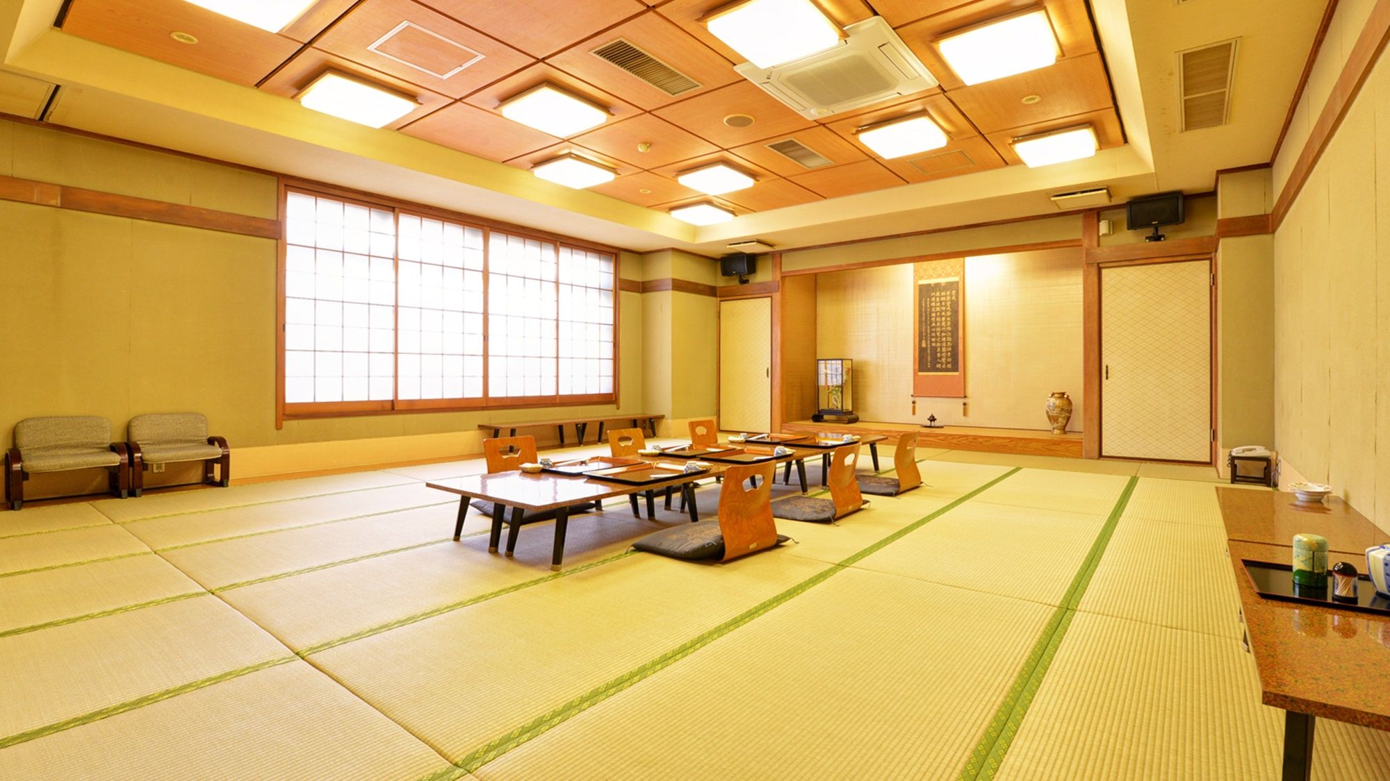 A traditional Japanese meeting room with tatami flooring, low tables, and sliding doors.