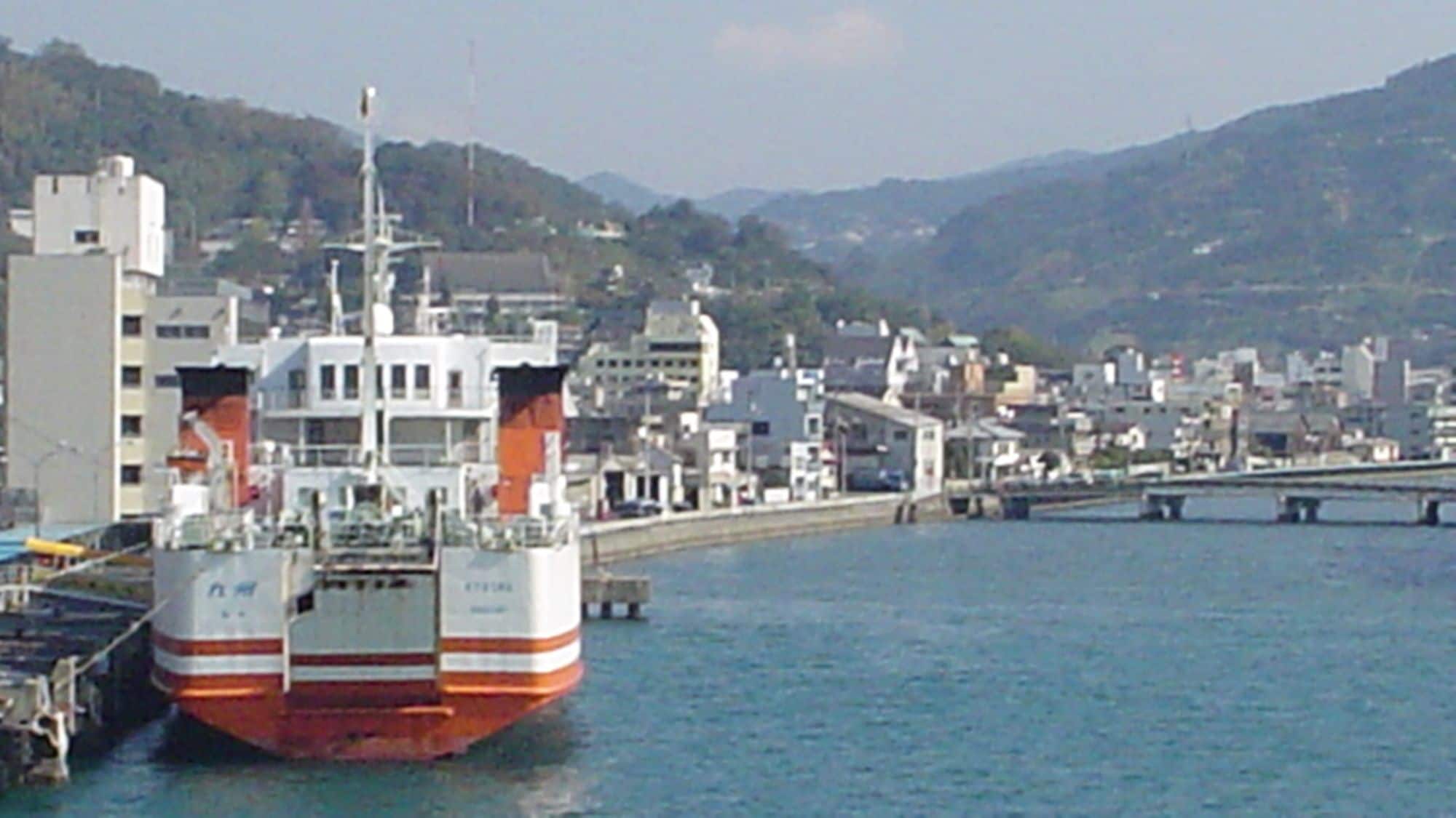 A ferry docked at a port with a cityscape in the background.