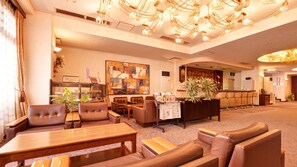A hotel lobby with leather seating, a reception desk, a bar area, and a large abstract painting on the wall. - Yahatahama Century Hotel Ito (Yawatahama)