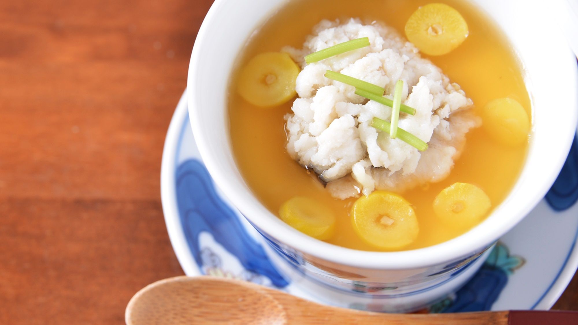 A bowl of soup with a spoon on a table.