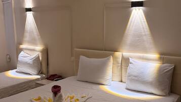A hotel room with two beds, a wall-mounted air conditioner, and a decorative towel arrangement on the bed.