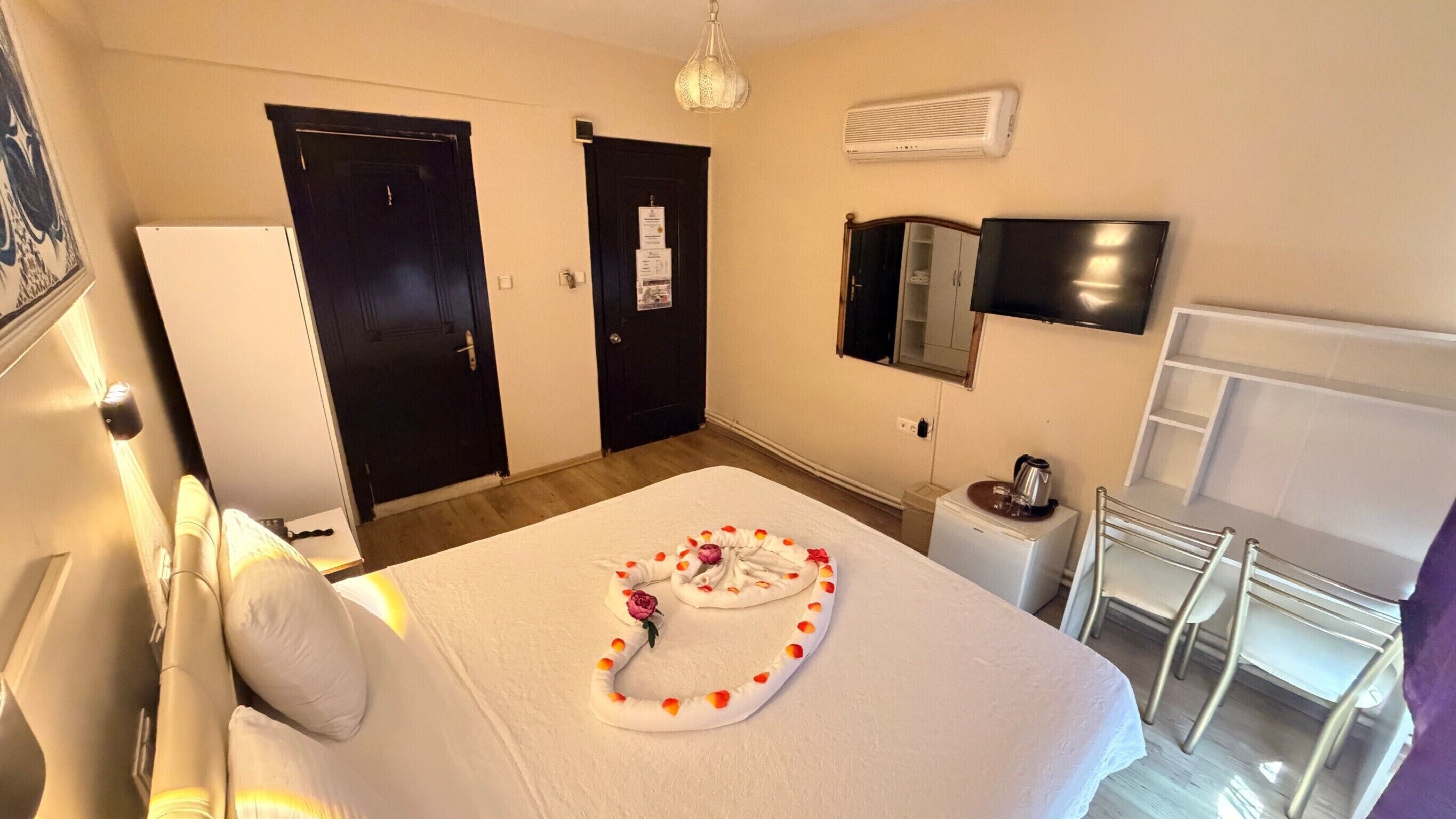 Ein Hotelzimmer mit Bett, Schreibtisch, Stuhl, Kühlschrank und Fernseher.