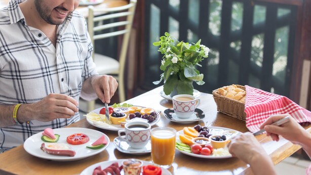 Une table mise pour le petit-déjeuner, avec des assiettes remplies de nourriture, une tasse de café et un panier de pain.