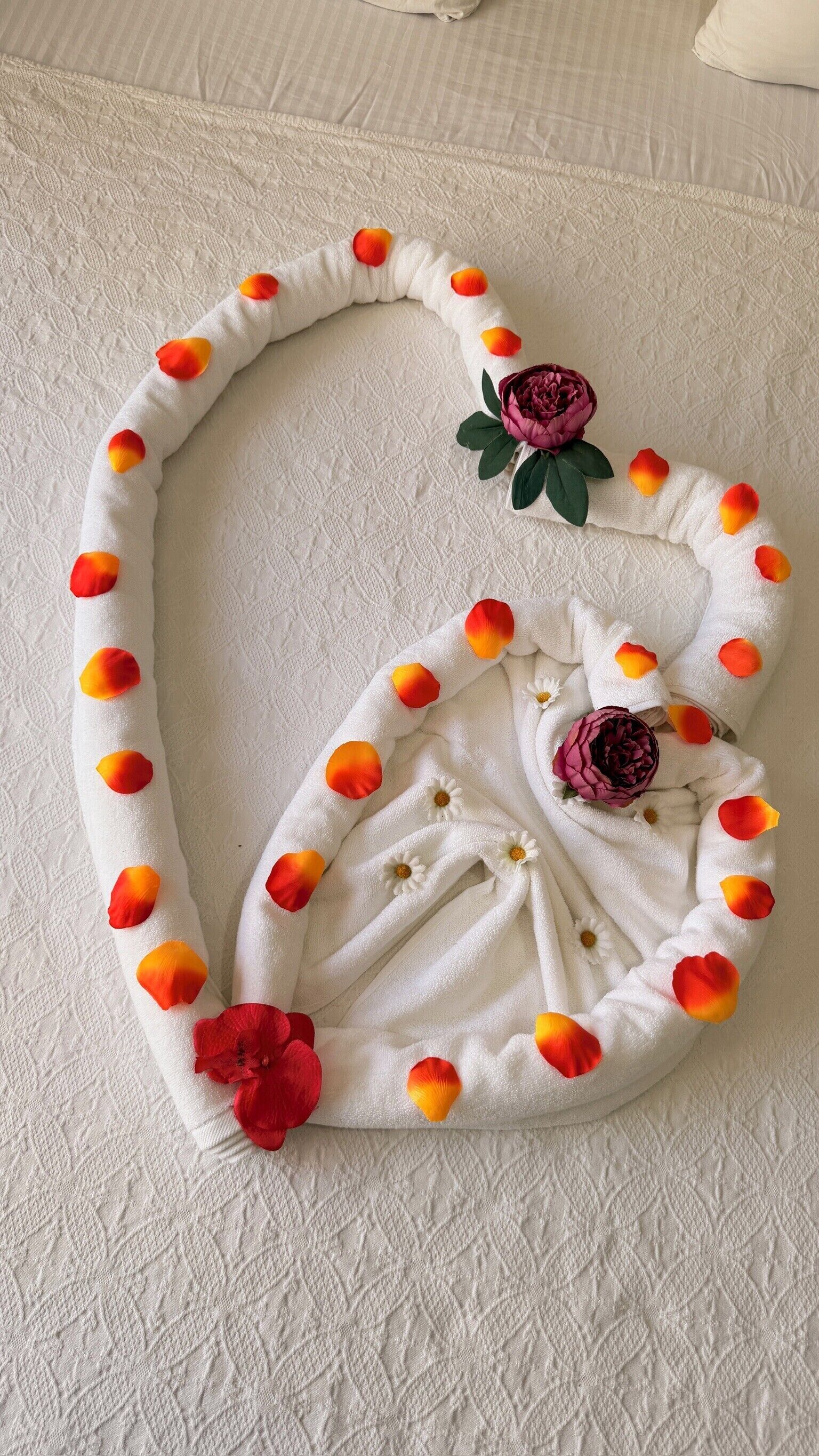 Una colcha blanca con textura y un arreglo en forma de corazón de elementos decorativos.
