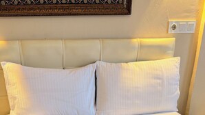 Un lit bien fait, avec du linge de lit blanc et des serviettes décoratives disposées en forme de cygnes, agrémentées de fleurs rouges.