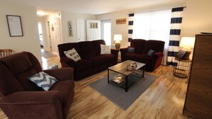 A living room with a brown sofa, a coffee table, and a lamp. There is a door in the background leading to another room. - Comfortable lake living, pool access, 3 miles to marina (Monticello)