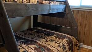 A bunk bed with a patterned bedspread, wooden headboard, and a window with sheer curtains. - Quiet, Comfortable Location! w/Double Garage
Easy access to WyoTech and UW (Laramie)