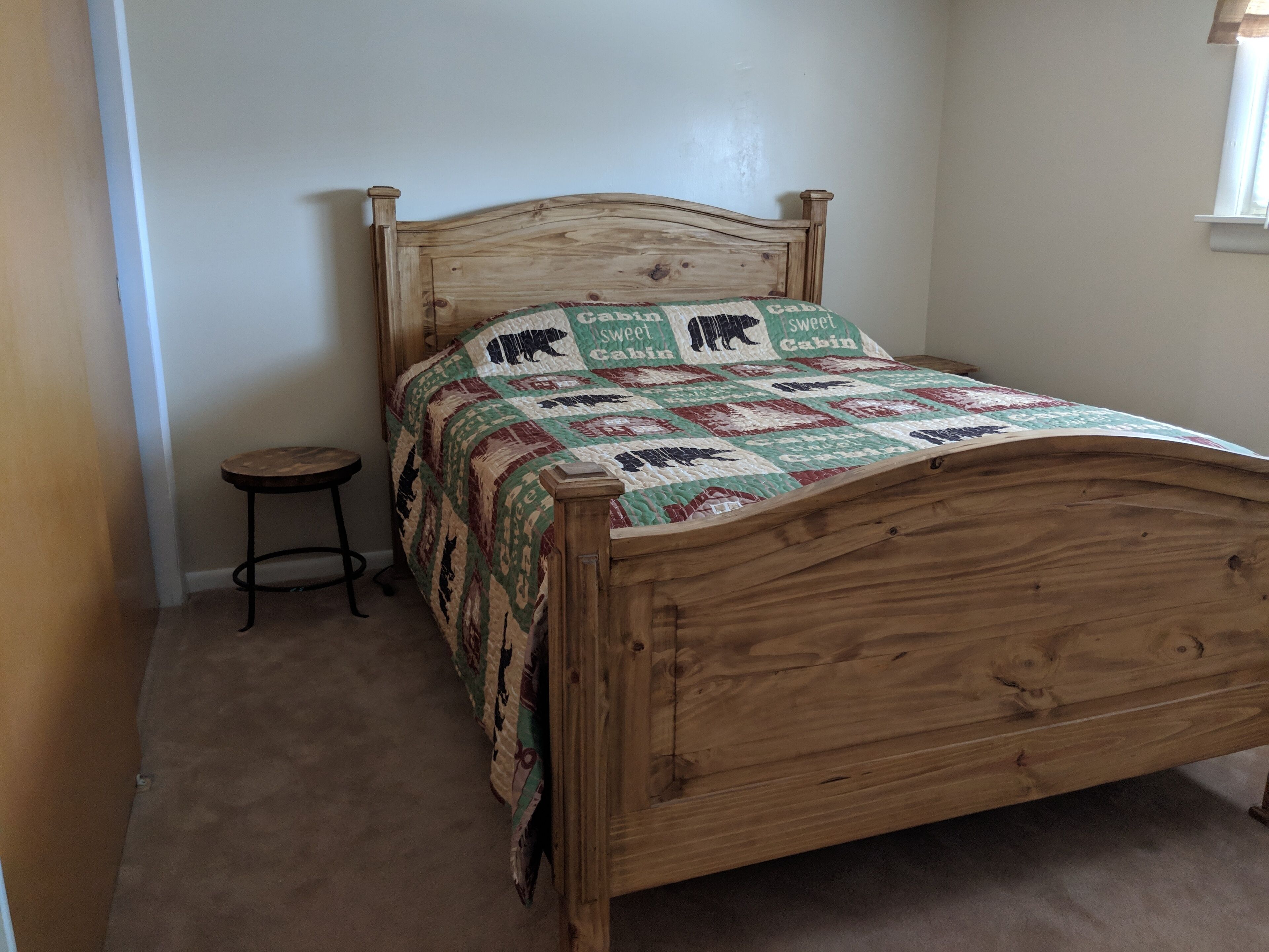 Una cama de madera con colcha de estampados de animales y el texto "Sweet Cabin".