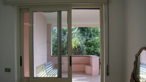 A room with a sliding glass door leading to a balcony with a view of greenery. - In the greenery of Fisciano large apartment in villa (FISCIANO)