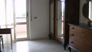A room with a wooden dresser, a chair, and a door leading outside. - In the greenery of Fisciano large apartment in villa (FISCIANO)