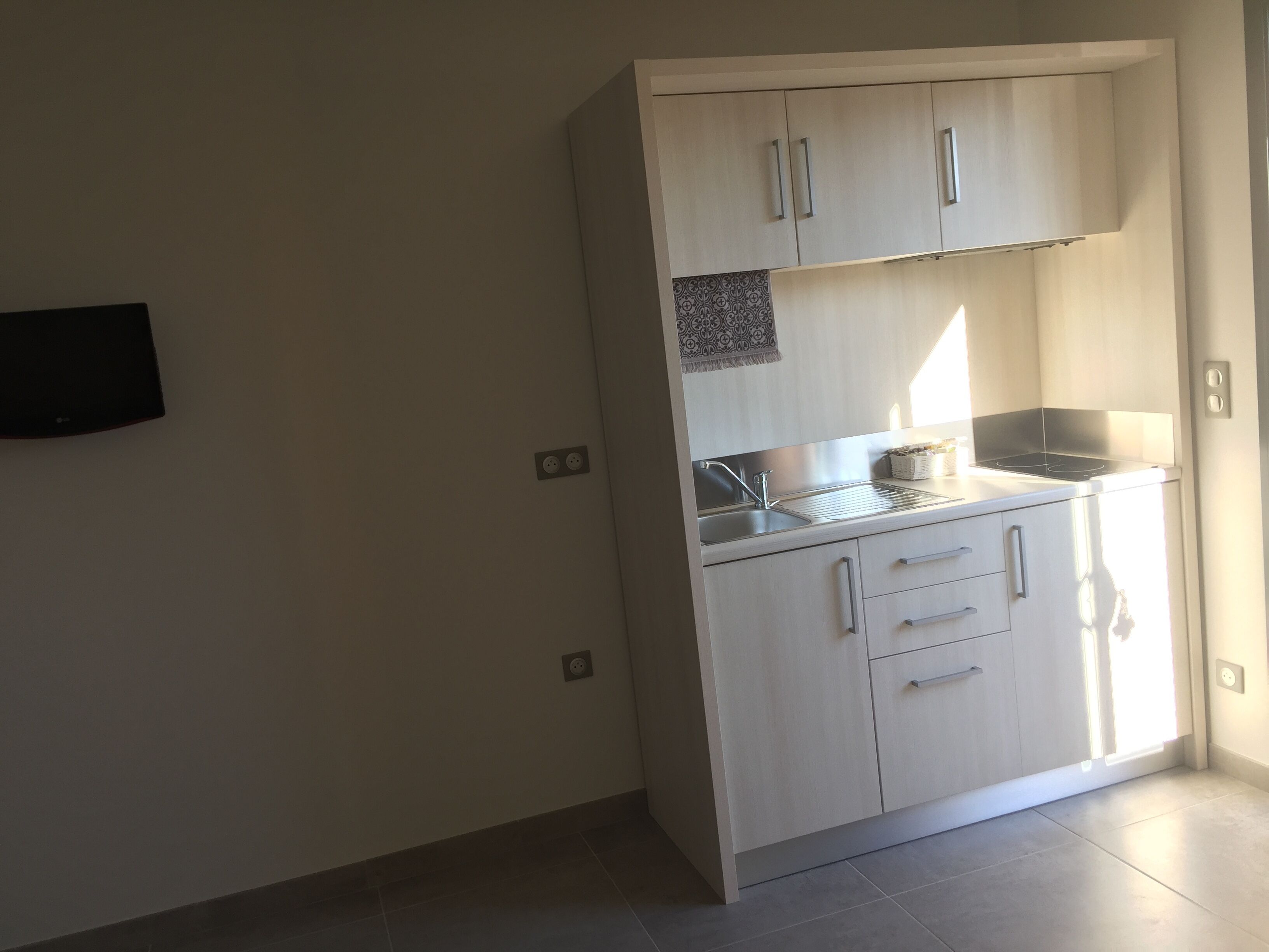 Une cuisine de taille réduite avec des meubles blancs, une cuisinière encastrée et un évier.