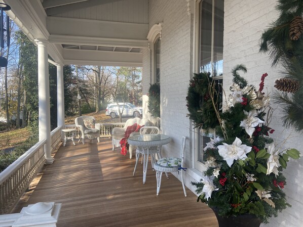 A covered porch with wicker furniture and a Christmas wreath. - Susquehanna Manor Inn (Marietta)