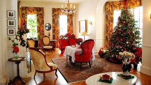 A dining area with red chairs, a Christmas tree, and a chandelier. - Susquehanna Manor Inn (Marietta)