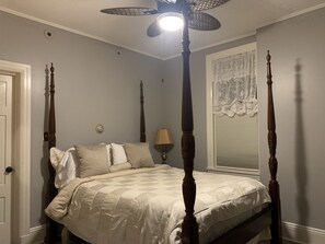 A four-poster bed with a quilted bedspread, a bedside lamp, and a window with lace curtains. - Susquehanna Manor Inn (Marietta)
