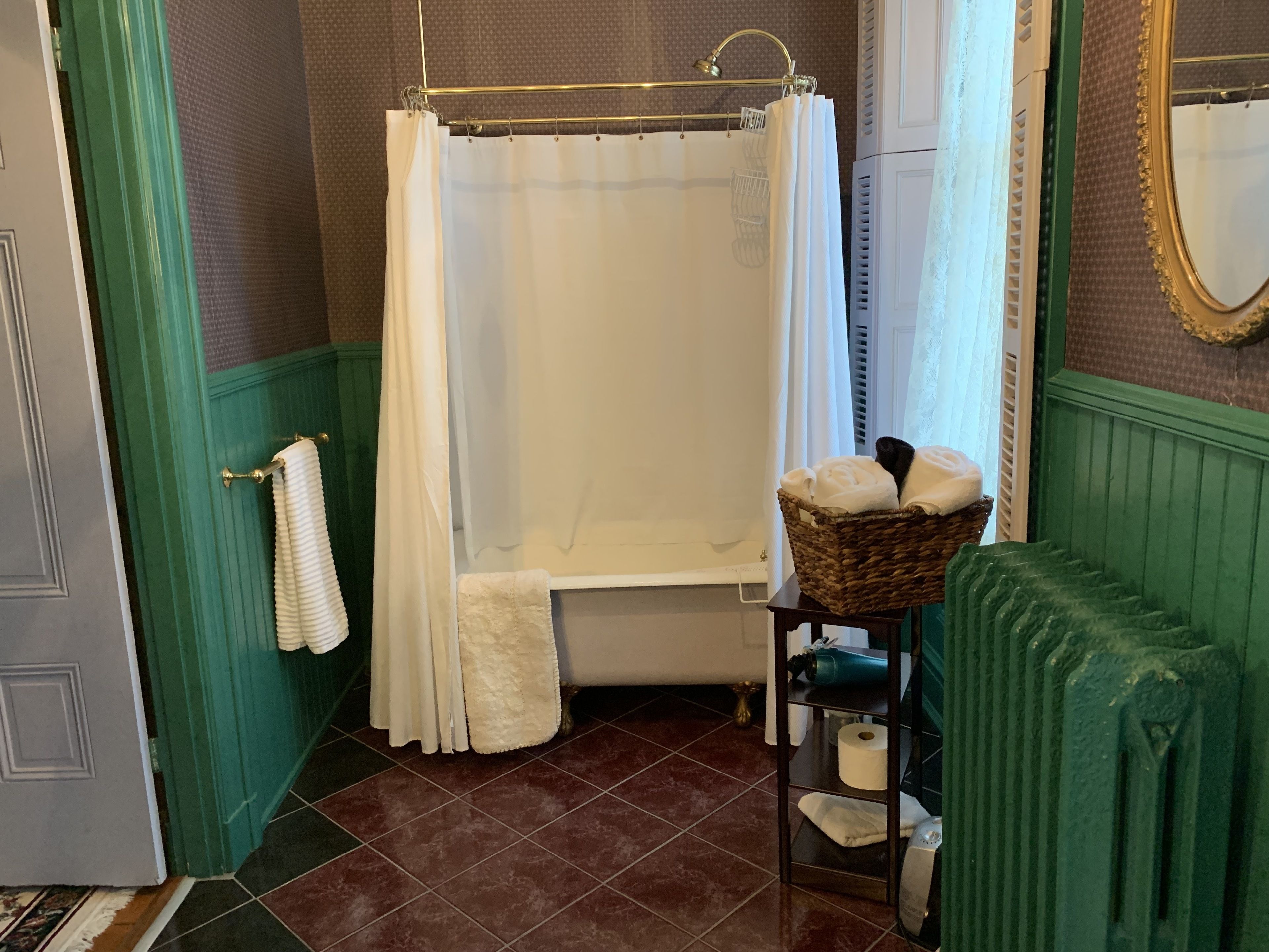 Ein Badezimmer mit einer Badewanne, einem Handtuchhalter, einem Heizkörper und einem Wäschekorb mit Handtüchern.