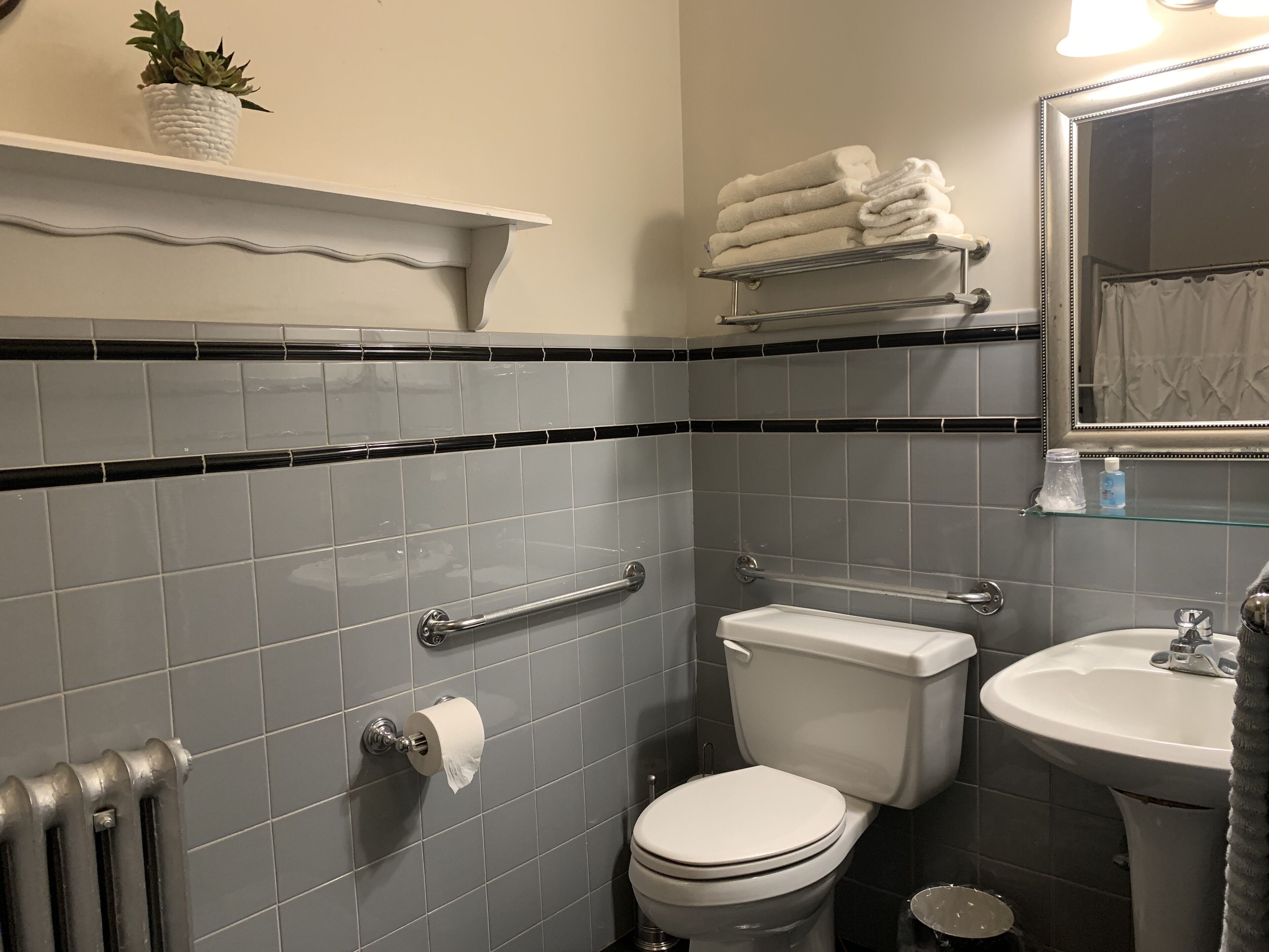 Un baño con inodoro, lavamanos y toallero.