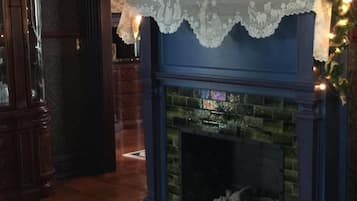 A cozy living room with a fireplace, a television displaying a Christmas message, and a decorative garland.
