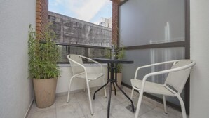 A small balcony with two white wicker chairs, a small table, and two potted plants. - San Juan Flat 33W (Rio Cuarto)