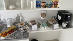 Un bufé de desayuno con diversas opciones de comida, máquinas de café y una cafetera sobre el mostrador.