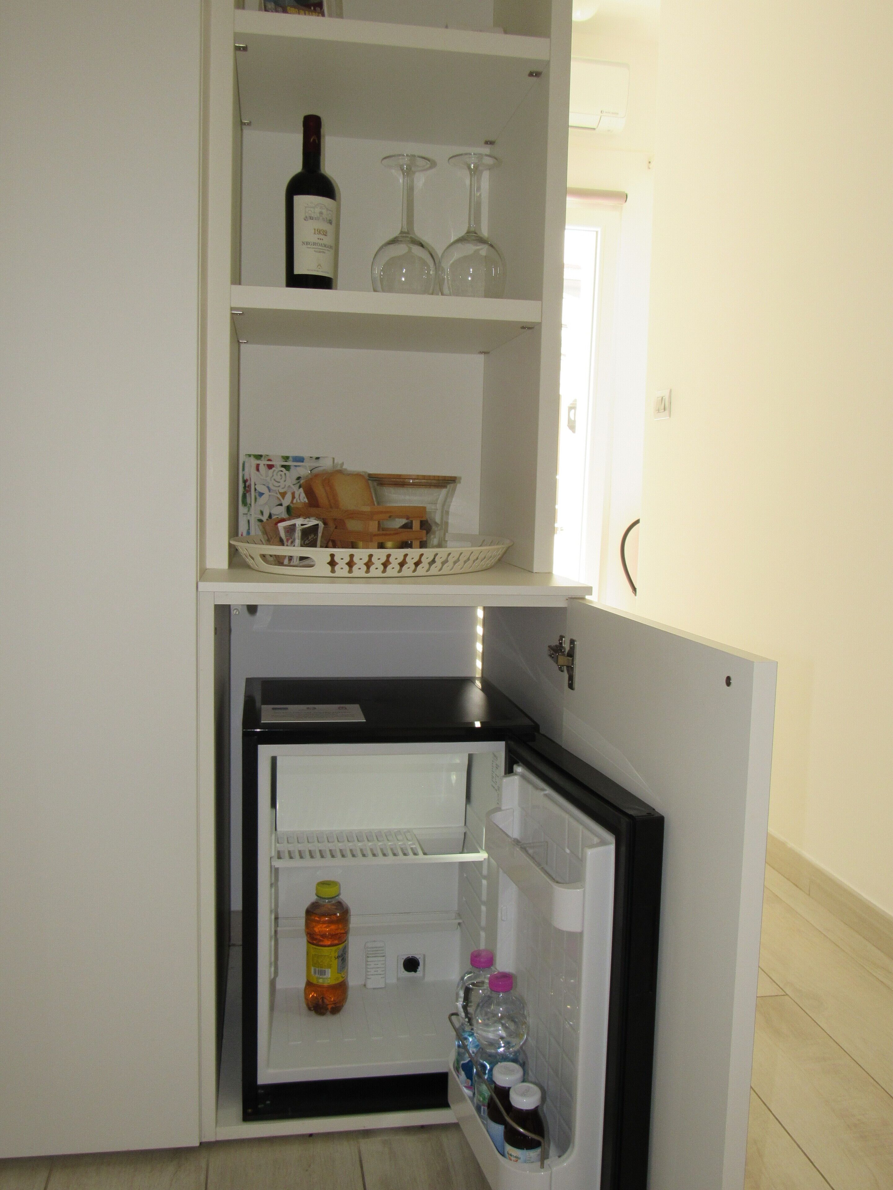 A compact refrigerator with a freezer compartment, containing various food items and beverages.