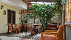 An outdoor patio with wooden furniture, a stone wall, and climbing plants. - Cabinas Coco Alegre (Sardinal)