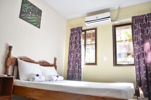 A single bed with a wooden headboard, white bedding, and purple curtains. - Cabinas Coco Alegre (Sardinal)