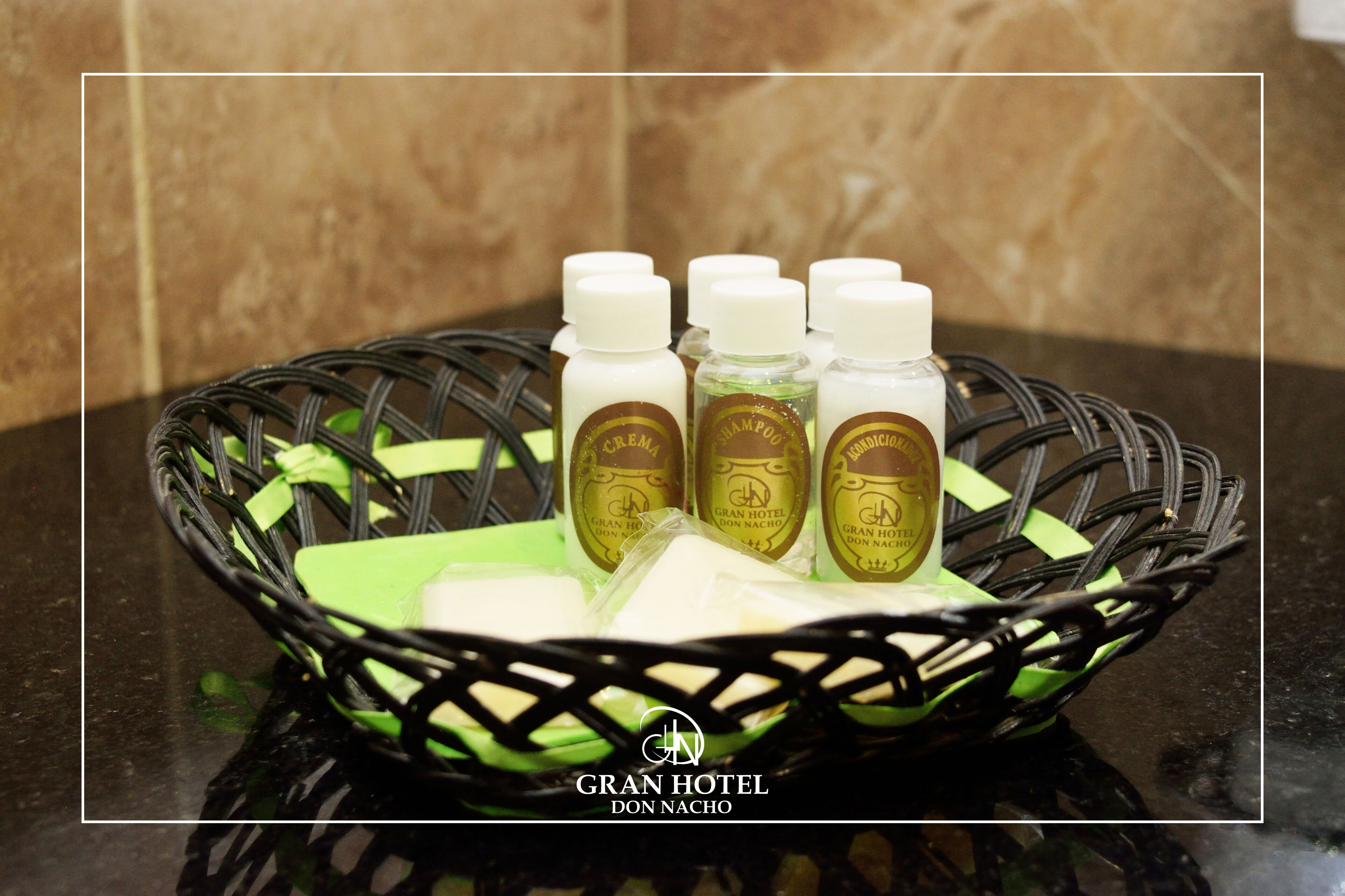 A wicker basket containing hotel toiletries on a marble countertop.