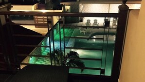 Un espace piscine agrémenté d’une barrière en verre, d’un escalier et offrant une vue sur la piscine.