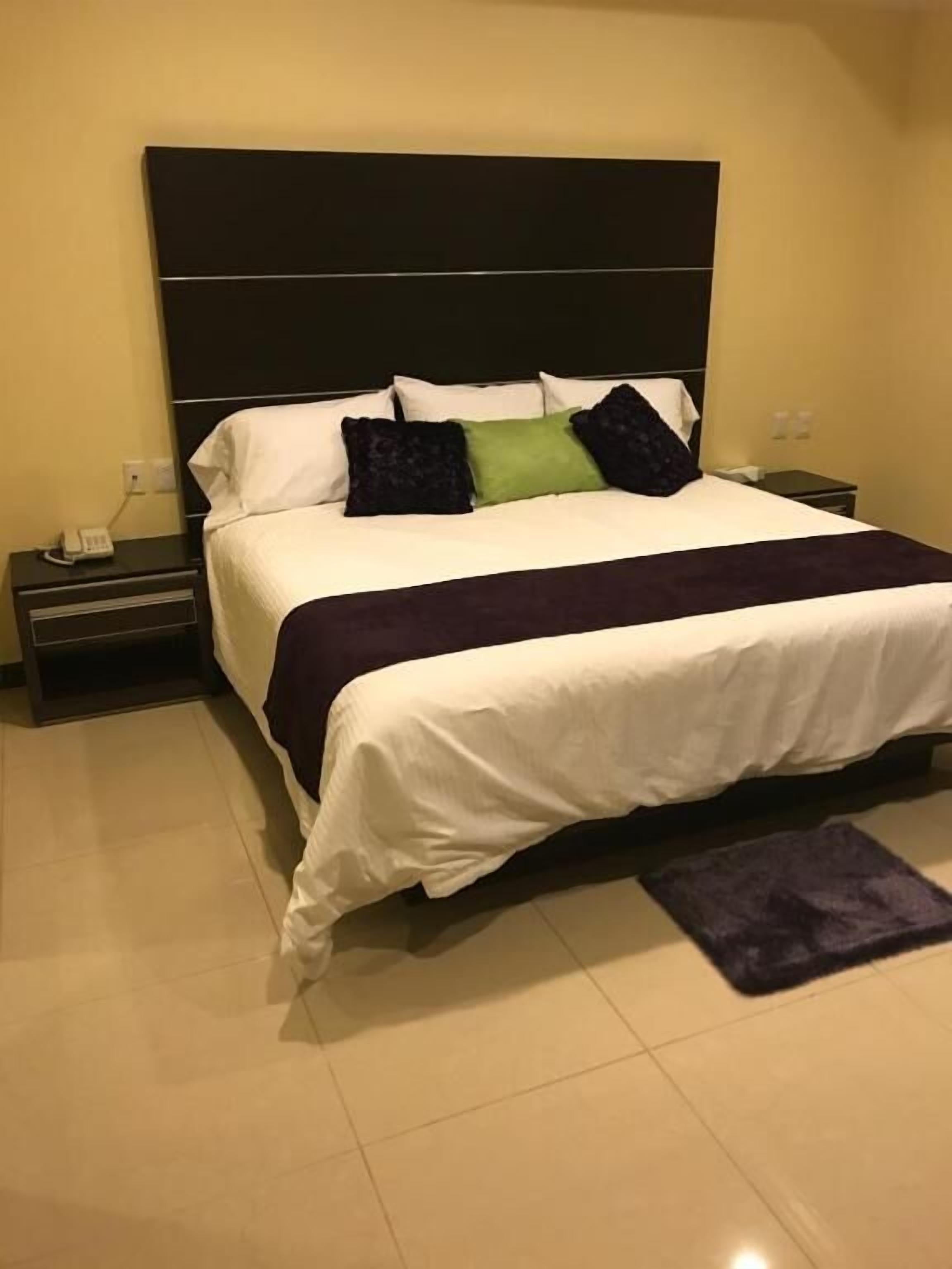 A hotel room with a large bed, a nightstand, and a bedside table.