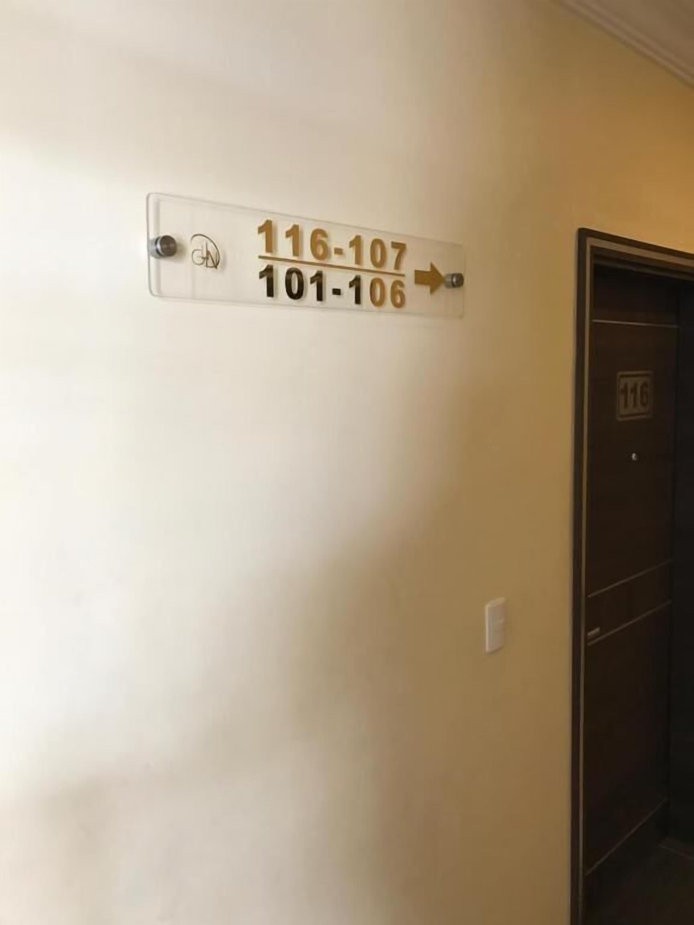 A wall-mounted sign with room numbers 116-107 and 101-106, indicating directions to different rooms.