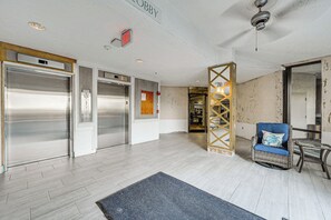 A lobby with two elevators, a reception desk, and a seating area with a blue sofa and a small table. - On-Site Beach Access! Waterfront Hudson Condo (Hudson)