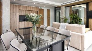 Een modern interieur met een glazen eettafel, comfortabele stoelen, een bank en een potplant.
