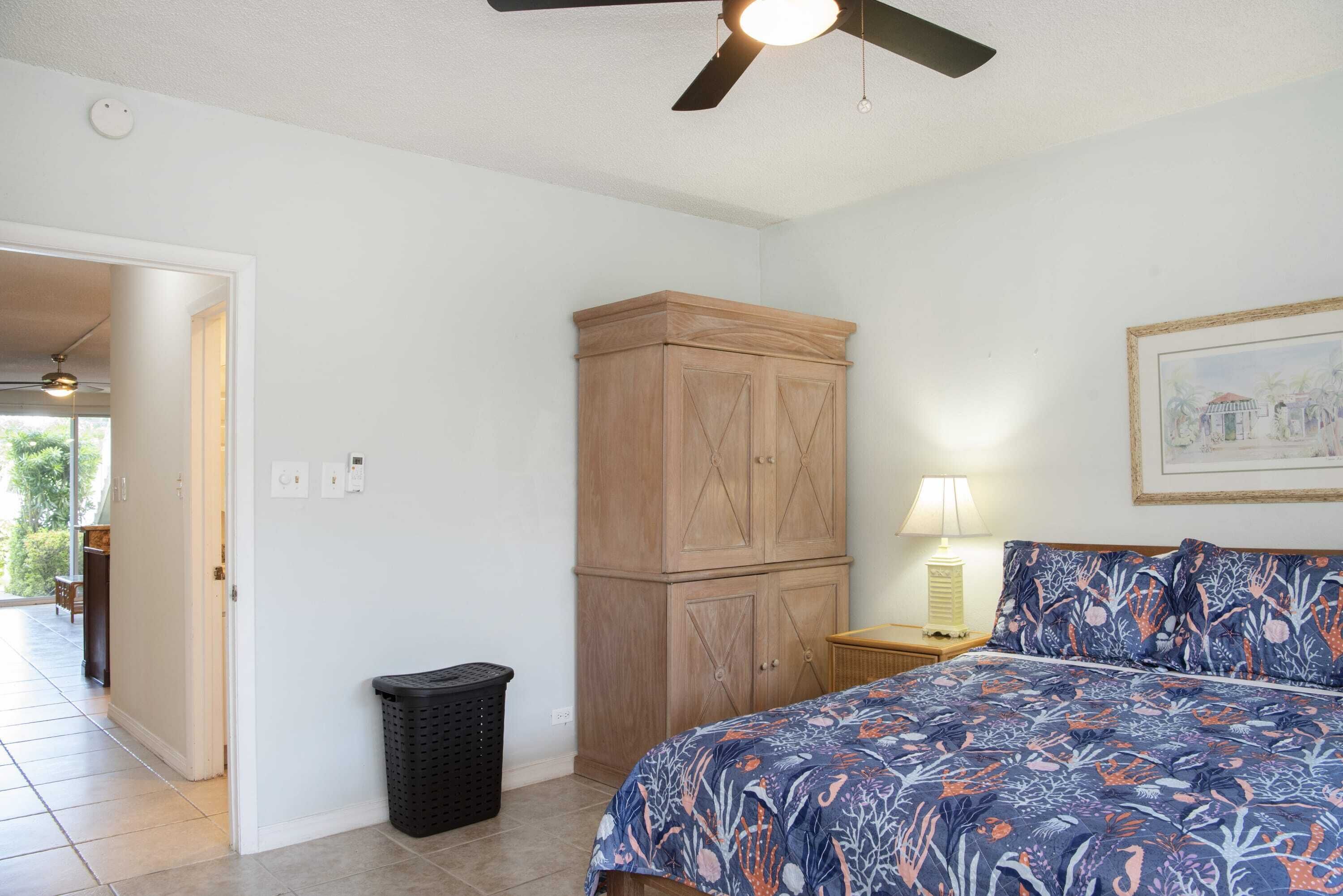 Un dormitorio con una cama, un armario de madera, una lámpara y un ventilador de techo.