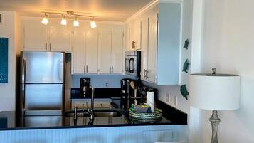 A modern kitchen with white cabinets, stainless steel appliances, and a bar area with stools.