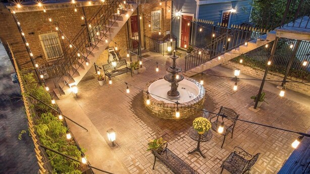 Un patio al aire libre con una fuente central, escalones de piedra y mobiliario exterior.