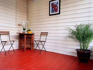 A corner with two wooden chairs, a small table, a potted plant, and a framed picture on the wall.