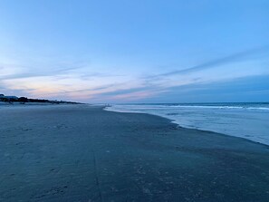 A wide beach with a clear sky and calm sea.