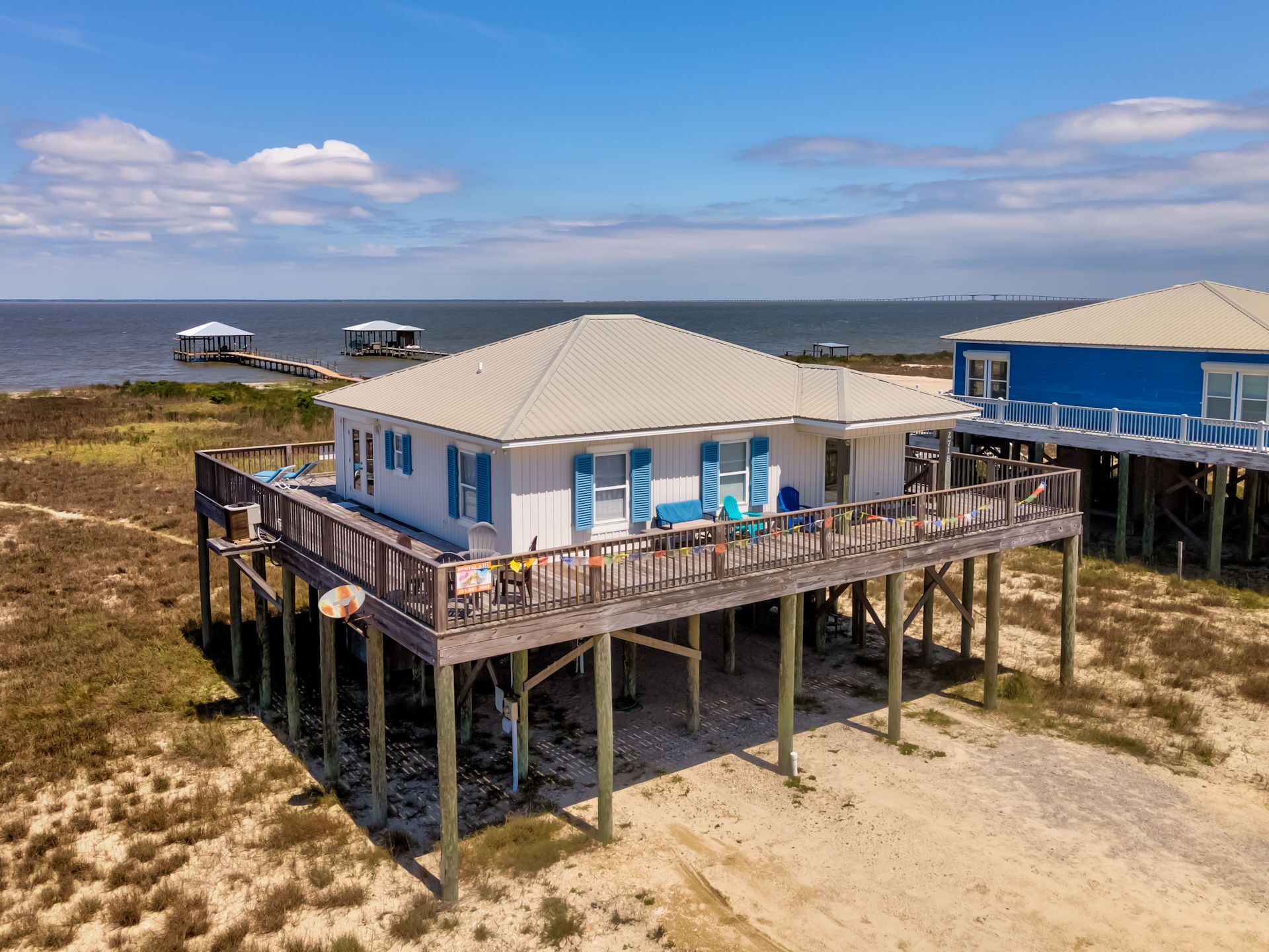 Une maison située en bord de mer, dotée d’un balcon, d’une jetée et offrant une vue sur l’océan.