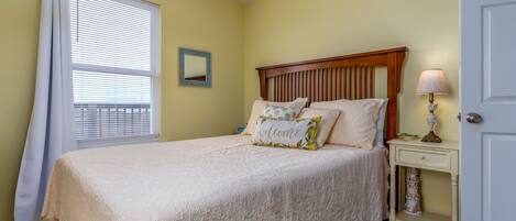 Un dormitorio con cama, mesita de noche, lámpara, puerta y ventana con persianas.